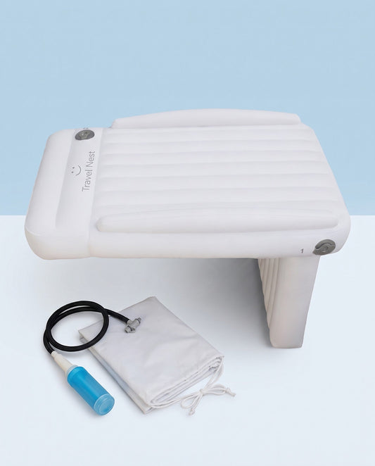 Travel Nest Kids Bed, an off-white inflatable airplane seat bed with raised side bumpers and a blue hand pump